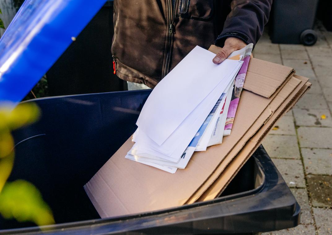 Oud papier wordt in de kliko gegooid
